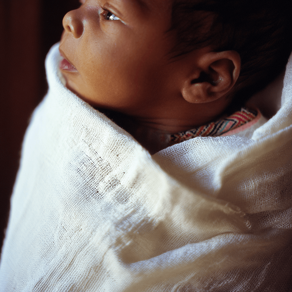 Ethiopian newborn wrapped in white netela with gold woven tibeb border