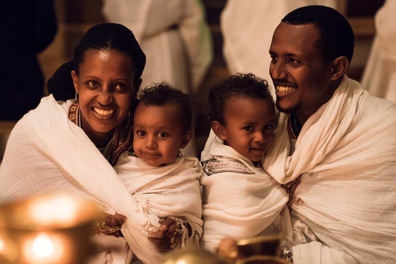 Ethiopian family with babies at holiday celebration by candlelight in white traditional dress