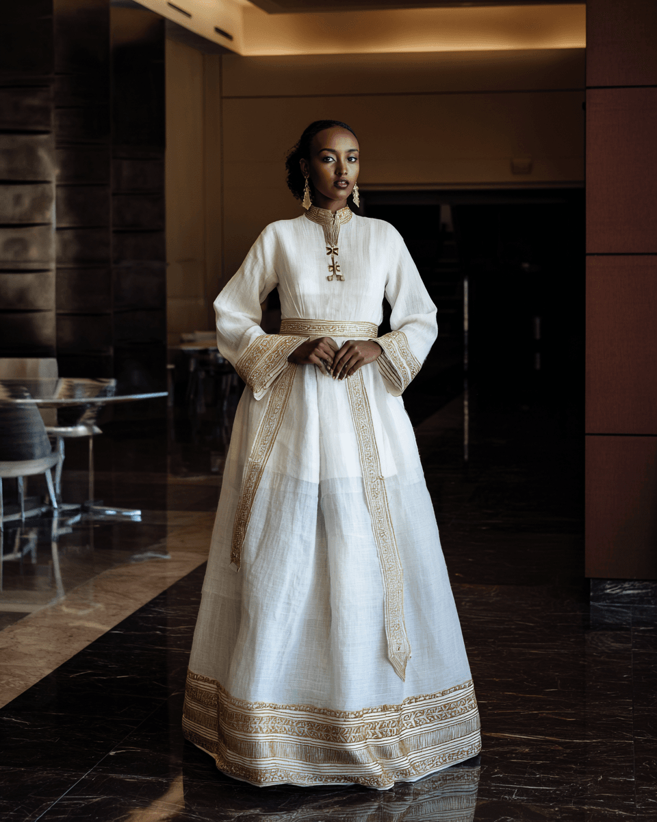 Ethiopian bride in elaborate white habesha kemis with gold tibeb border in hotel lobby